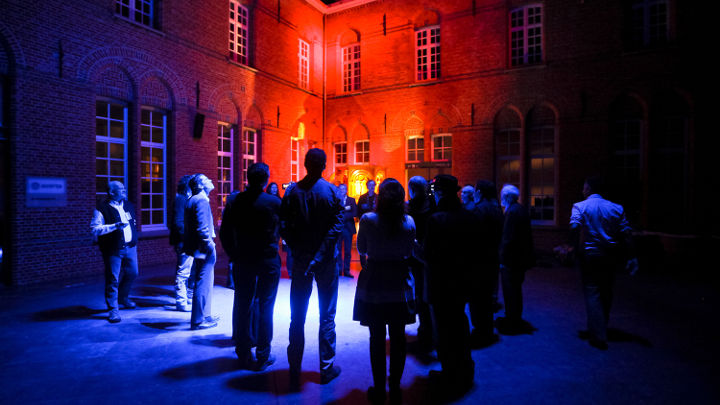 벨기에 Turnhout에서 열린 필립스 워크숍 참석자들이 멋지게 빛나는 한 건물 앞에서 토론하는 모습